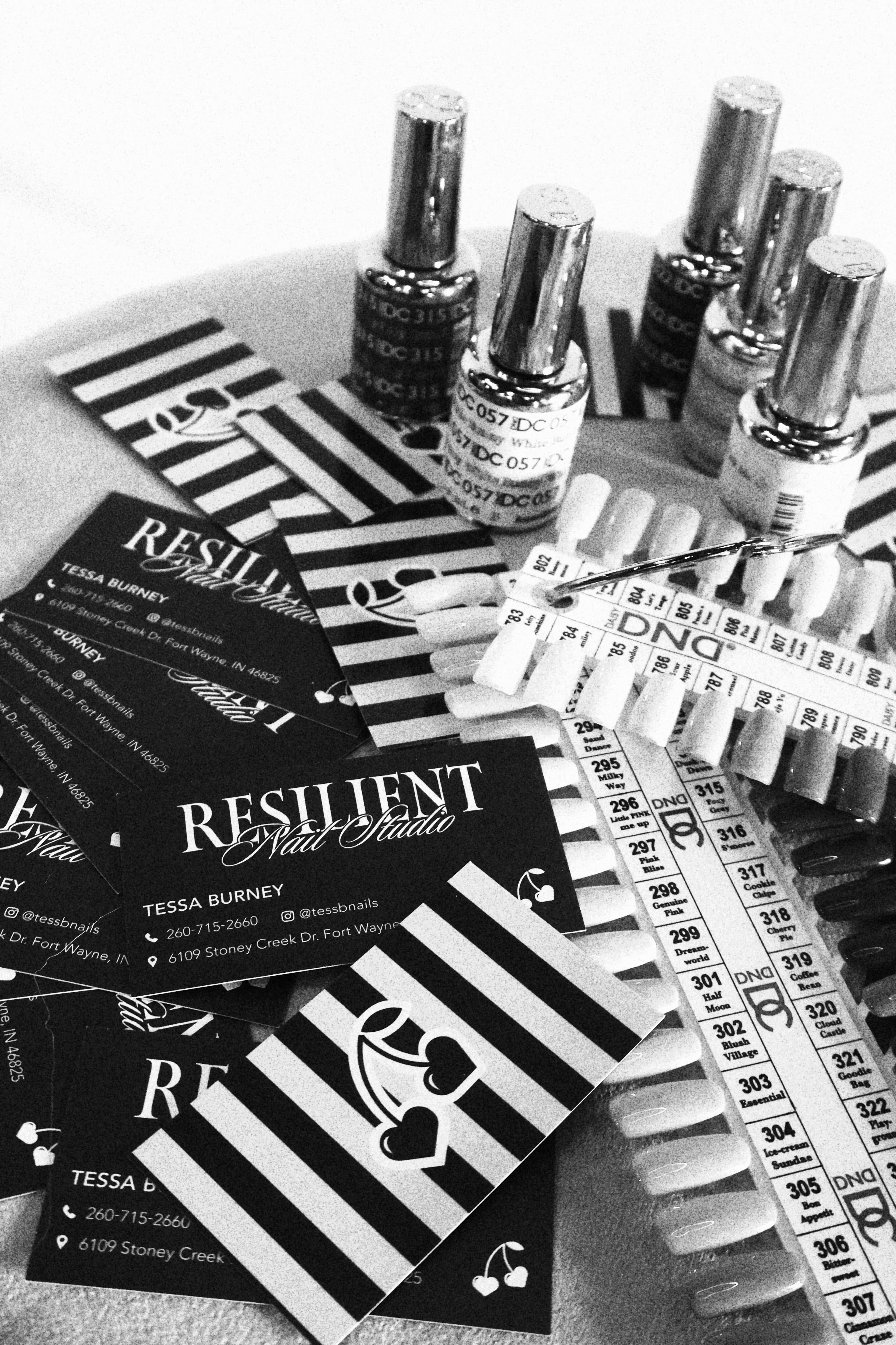 Resilient Nail Studio business cards, polish bottles, and nail color swatches arranged on a stool