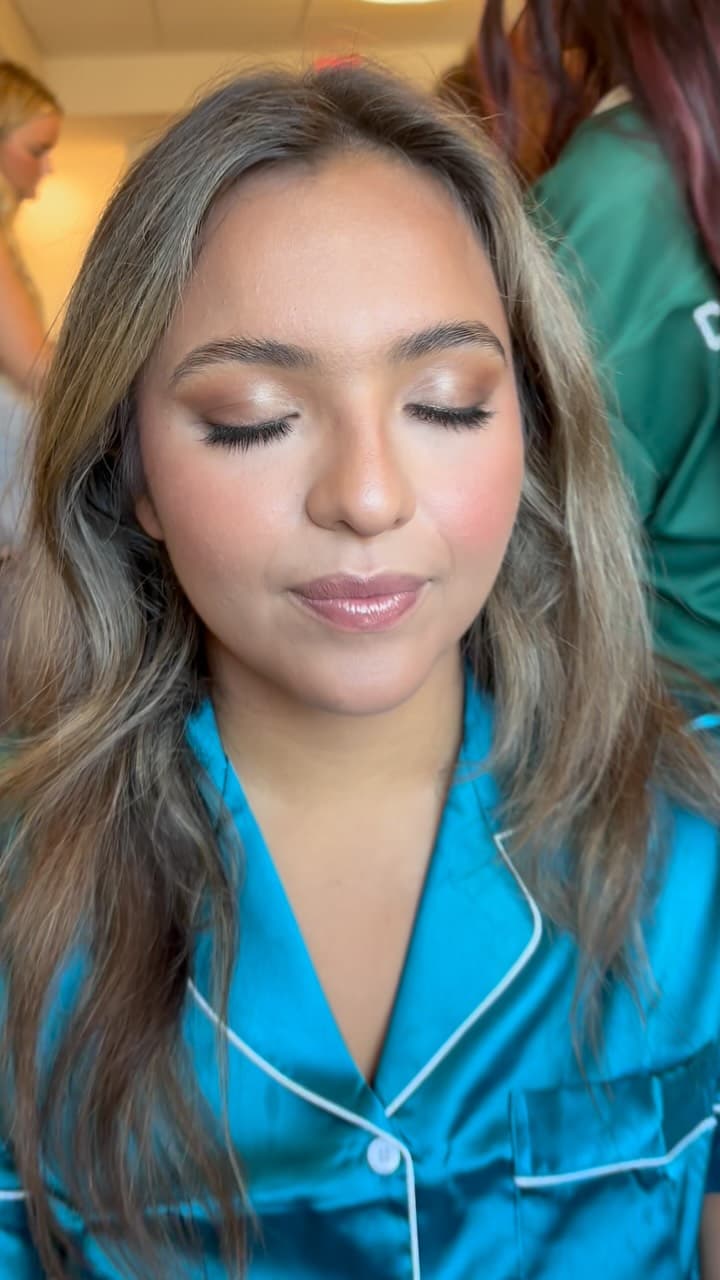 Bridesmaid having makeup applied in a satin robe