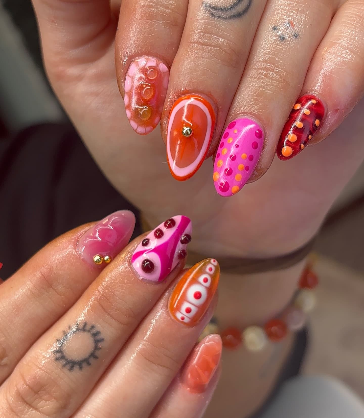 Colorful abstract nail art in pink, orange, and red